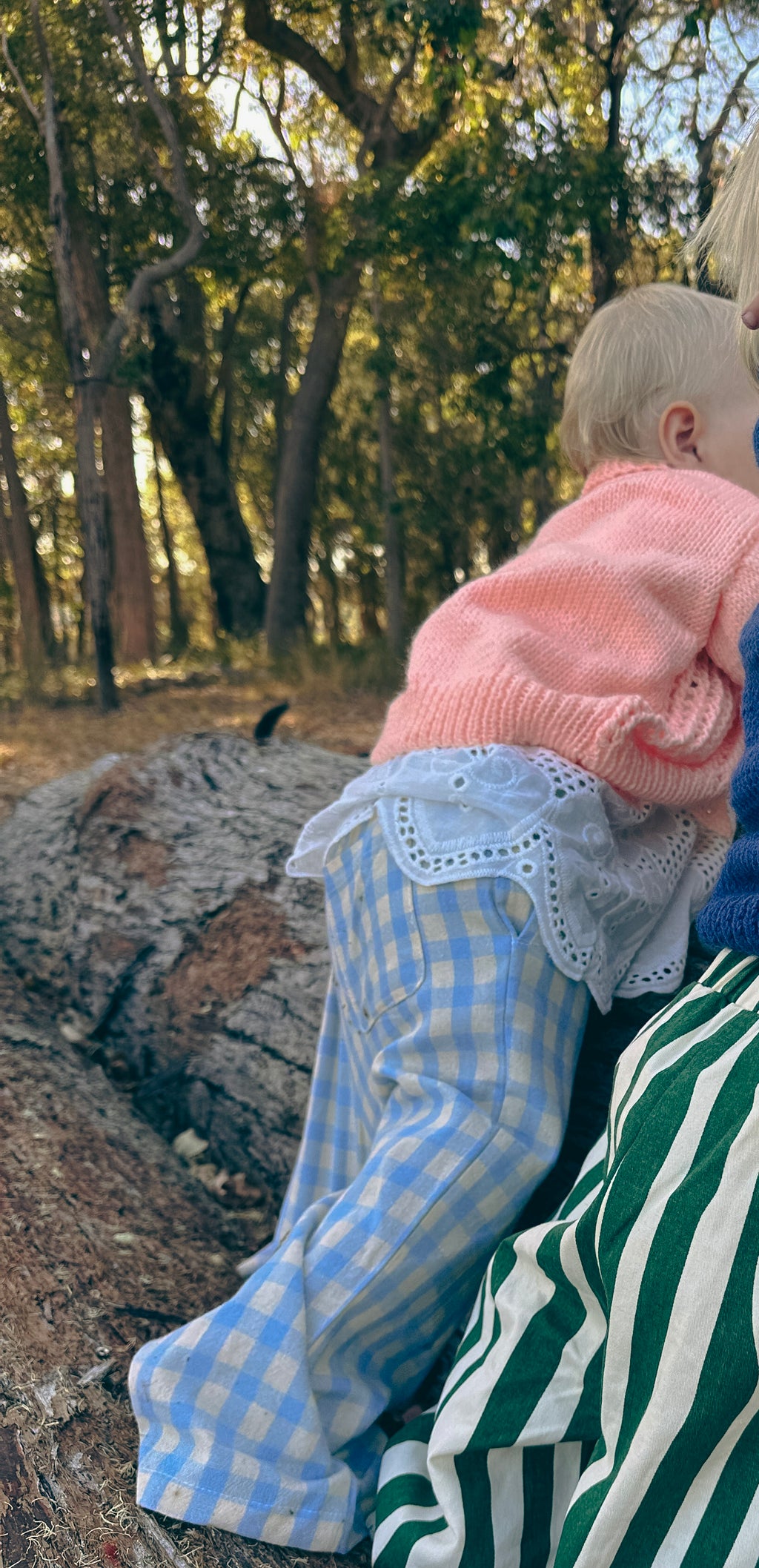 toddler standing on log in handmade orange knit cardigan 