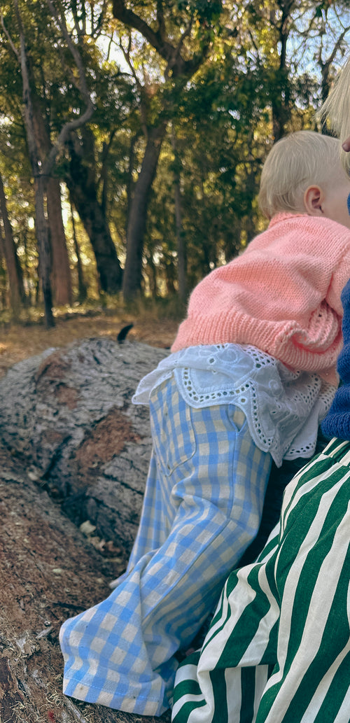toddler standing on log in handmade orange knit cardigan 
