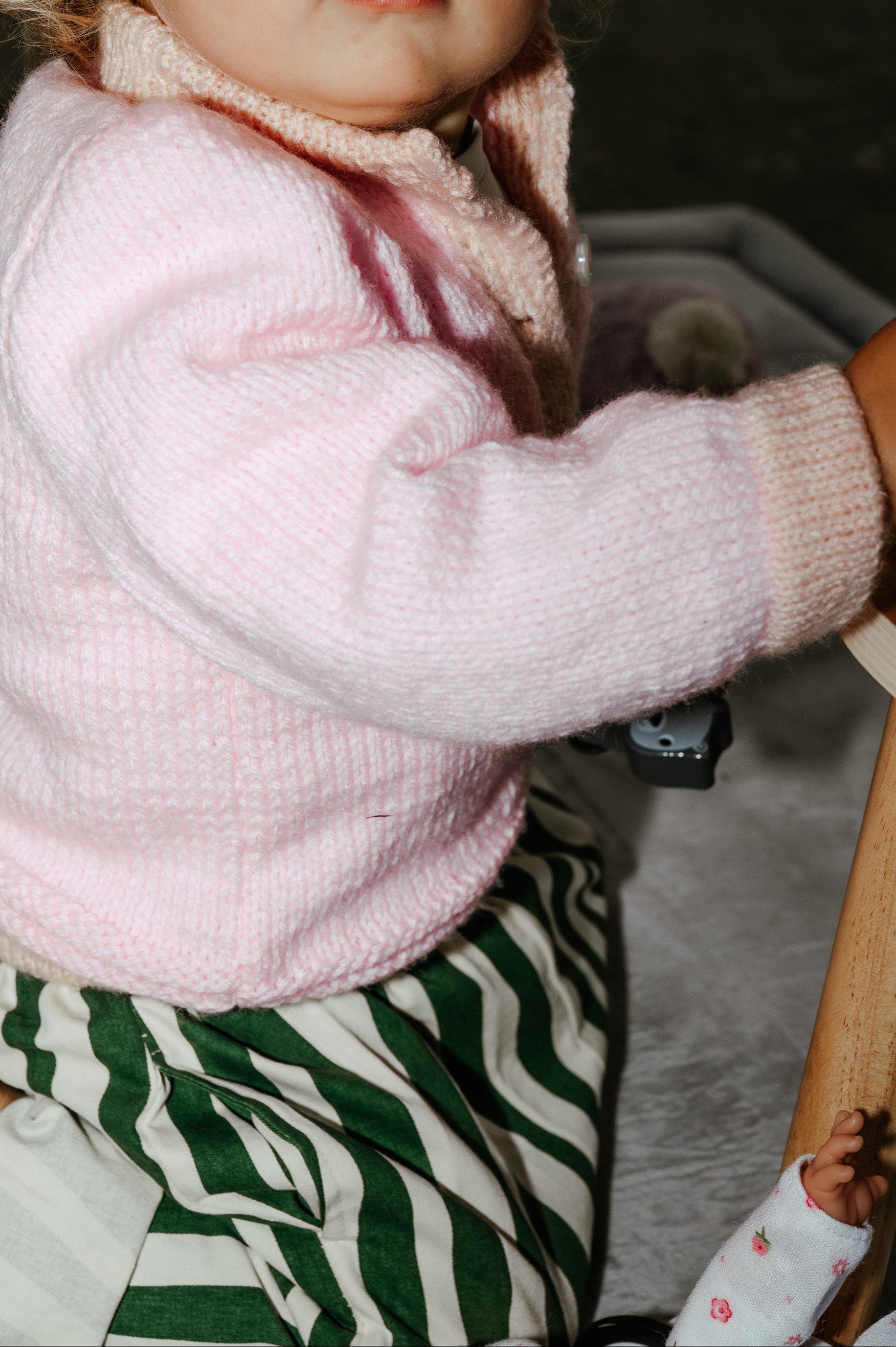 Child wearing a pink sweater and green zebra-striped pants 