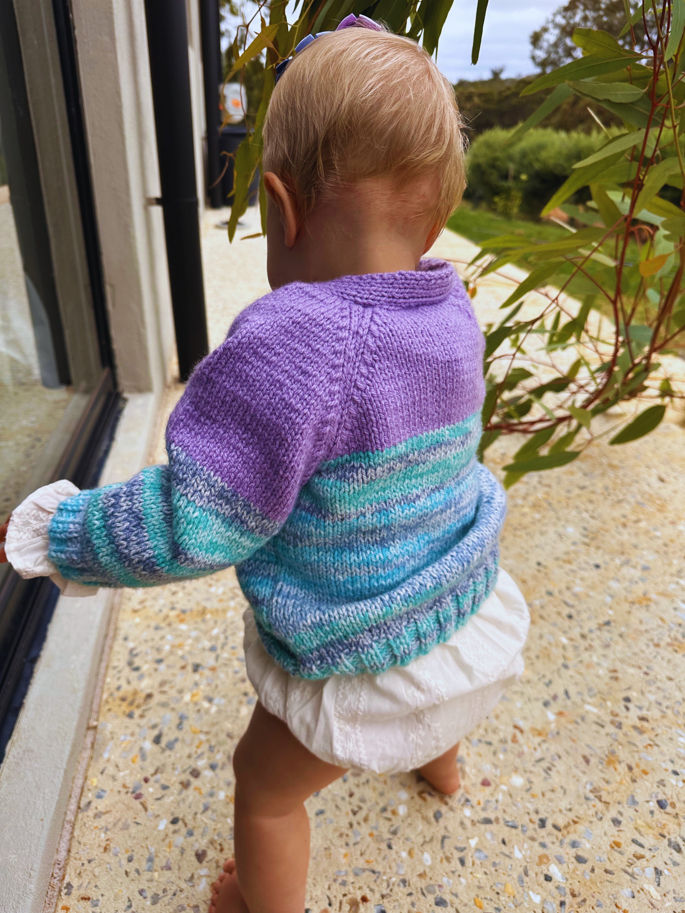Child wearing a purple and blue striped sweater outdoors