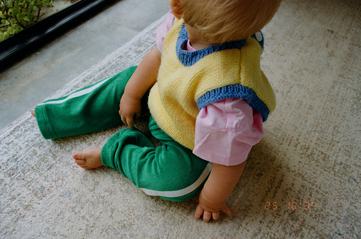 Child in colorful outfit sitting on a carpeted floor