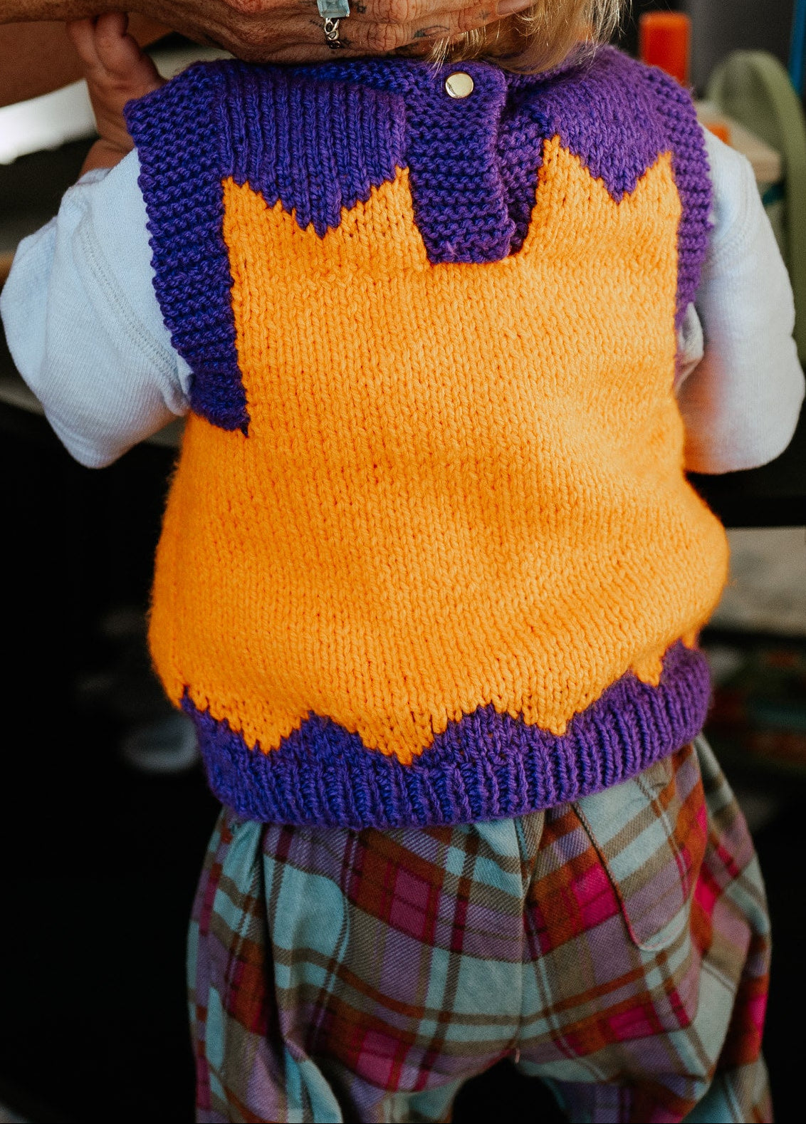Children in colorful sweaters playing with a toy in a home setting