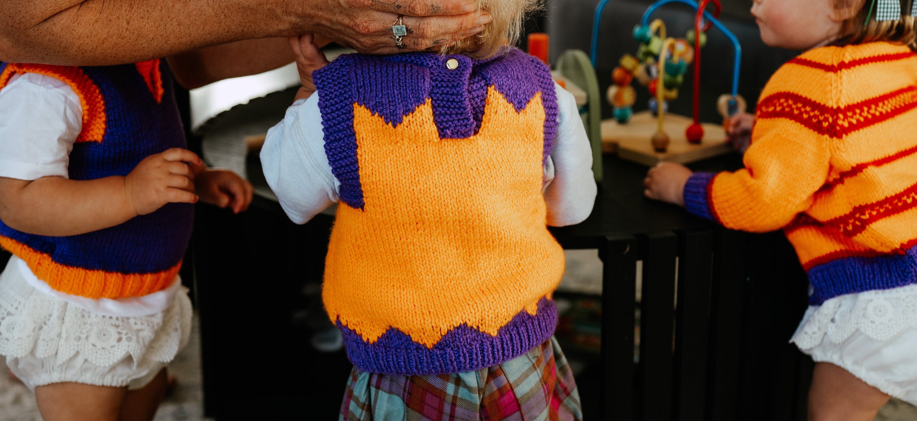 Children in colorful sweaters playing with a toy in a home setting