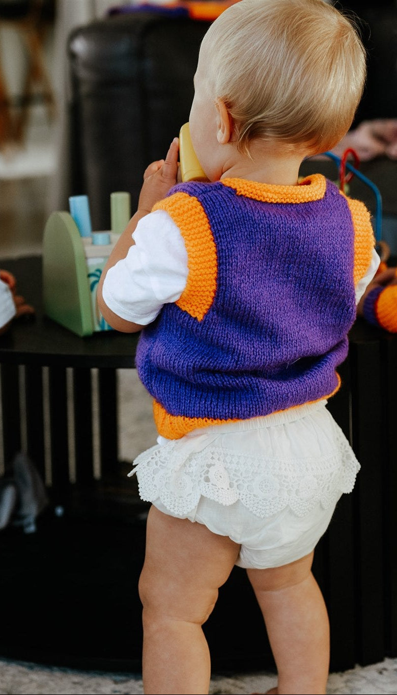 child in colourful vest playing indoors