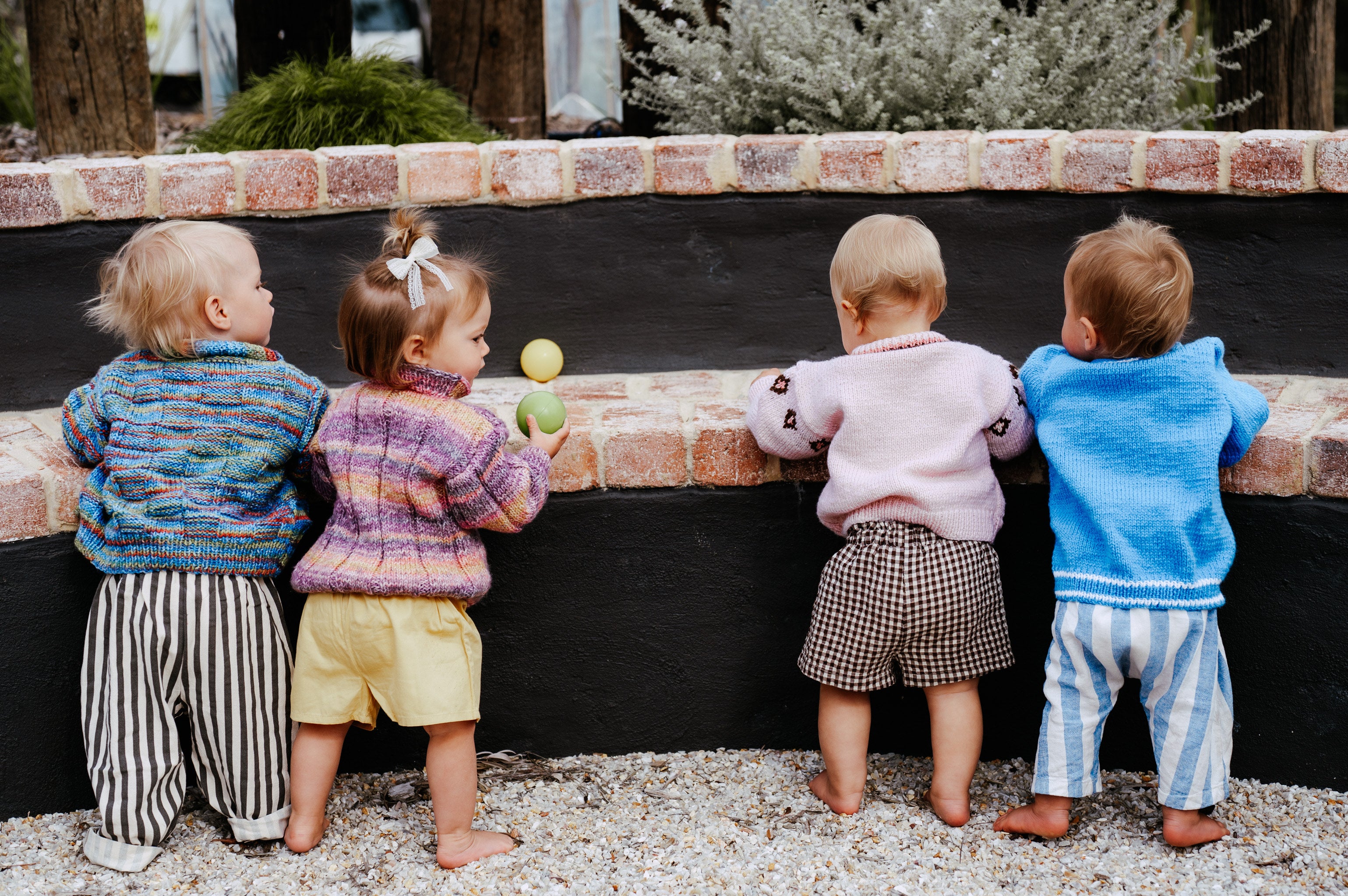 Four children standing on a stone path looking into a black pool.