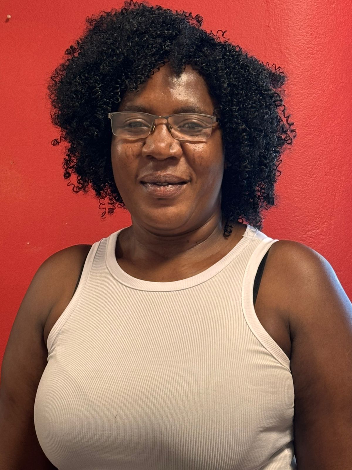 Sally smiling, wearing a white top against a red background